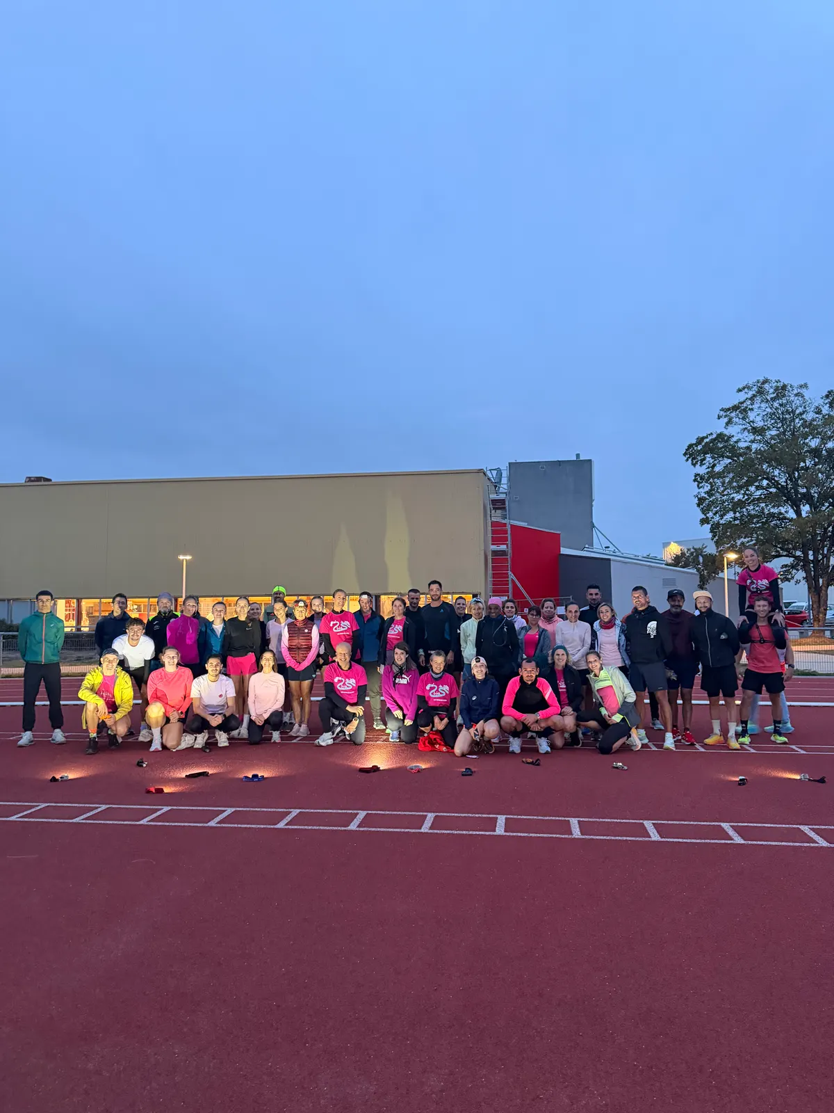 Les participants du Test VMA Octobre Rose réunis sur la piste d'athlétisme à la tombée du jour.