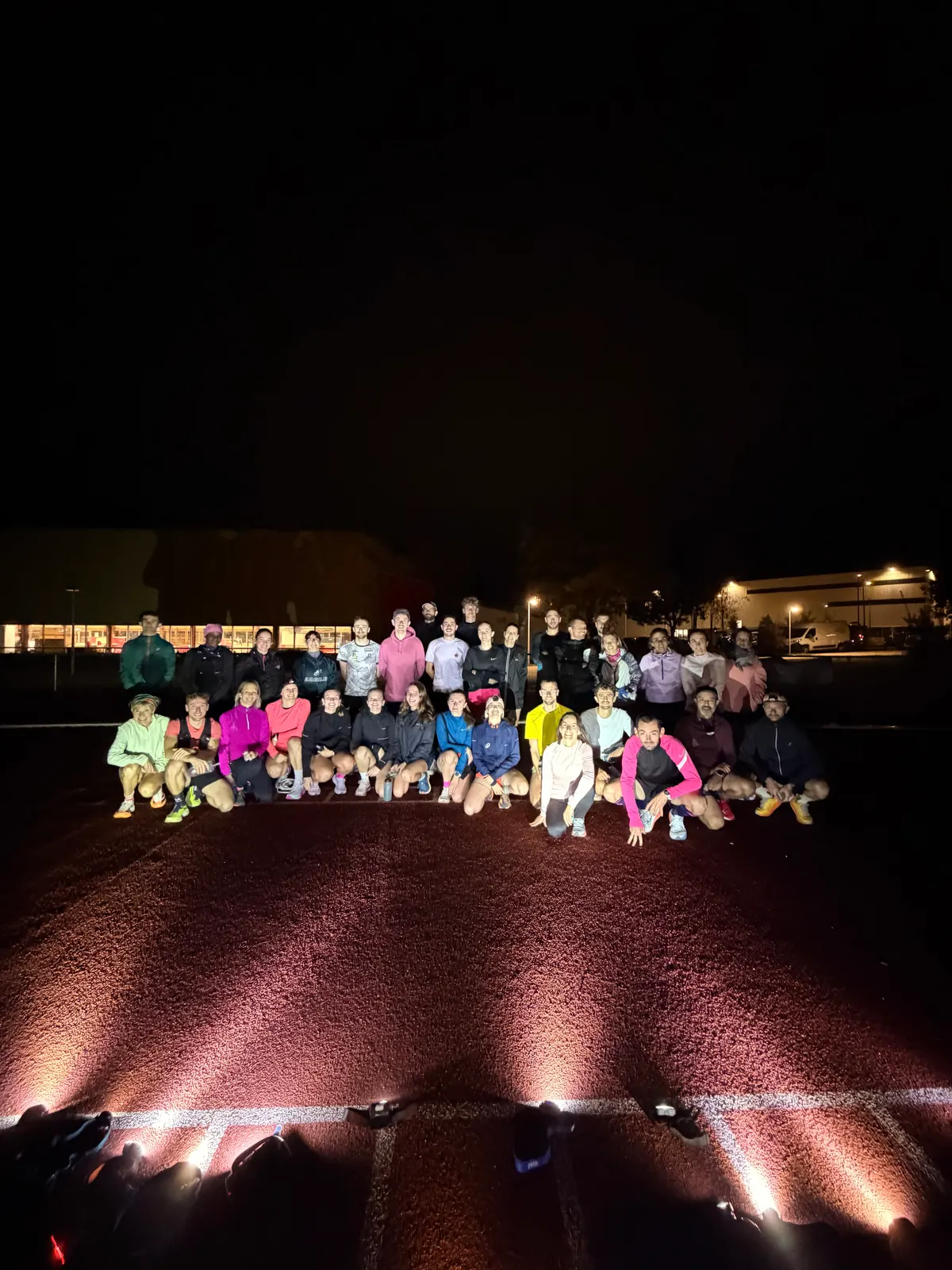 Photo de groupe de nuit après le Test VMA Octobre Rose, la piste éclairée au premier plan.